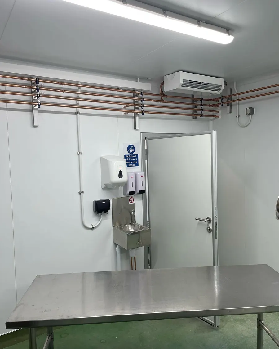 Ceiling-mounted air conditioning unit and copper runs in a commercial kitchen prep room