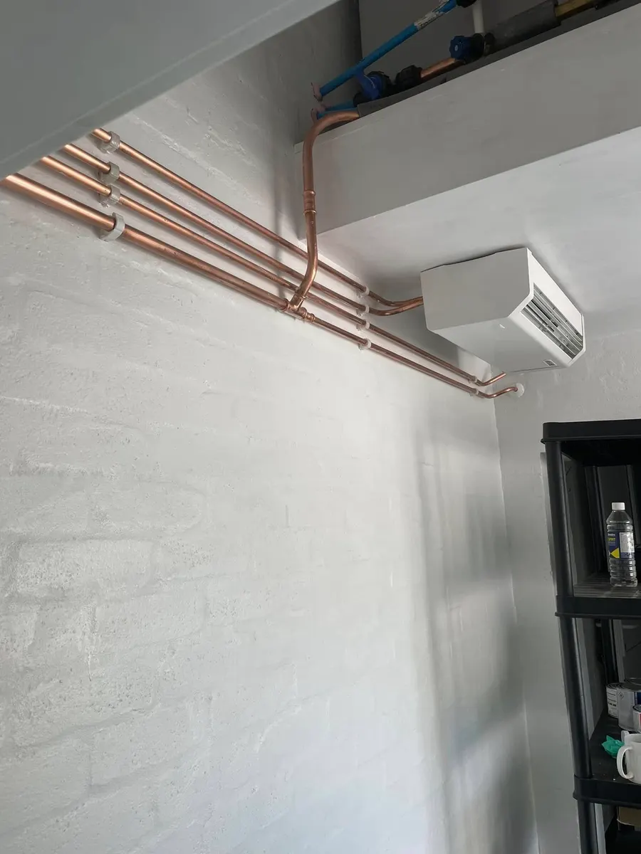 Wall-mounted air conditioning unit fed by neat copper pipe runs