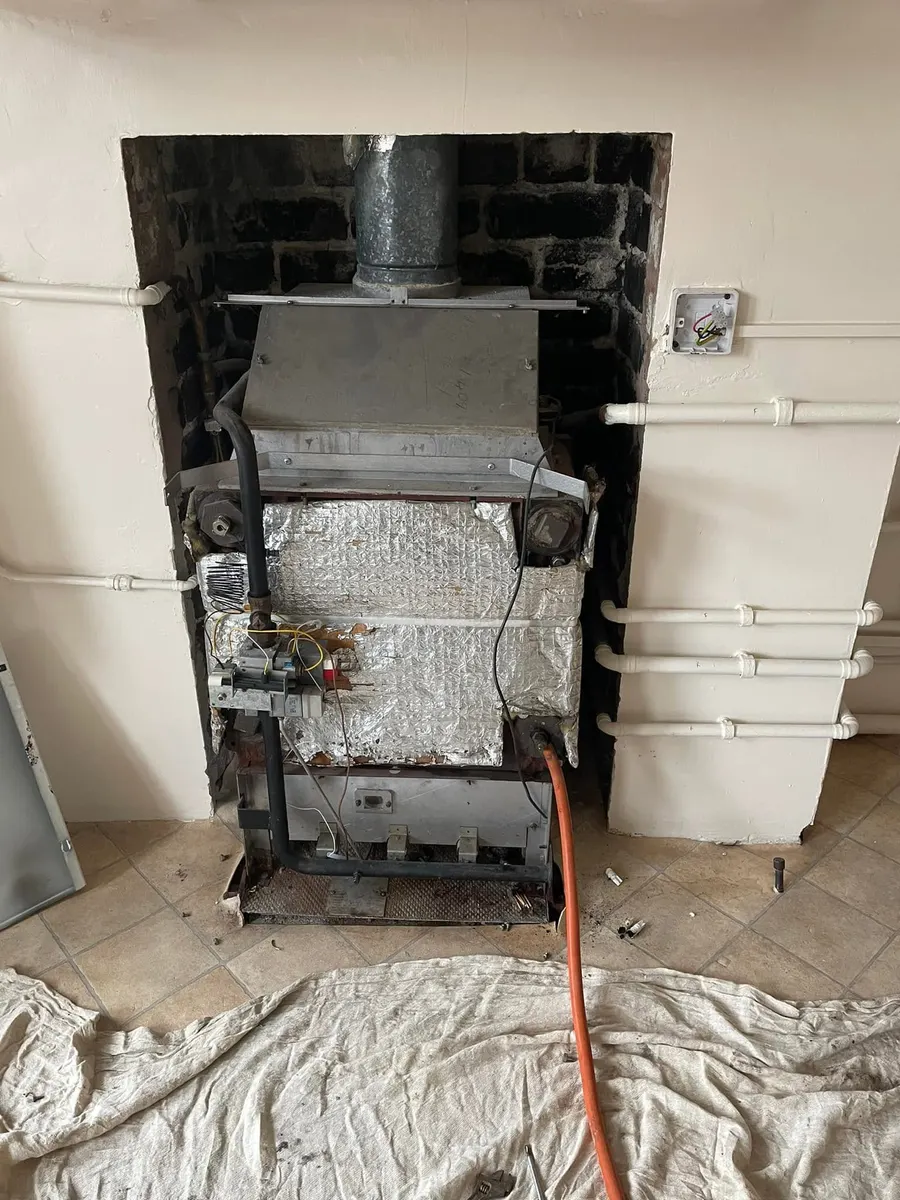 Before: old back boiler stripped out of the fireplace with foil insulation and exposed wiring