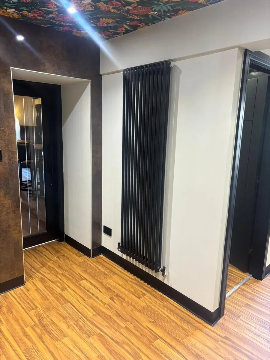 Tall black column radiator fitted in a hallway