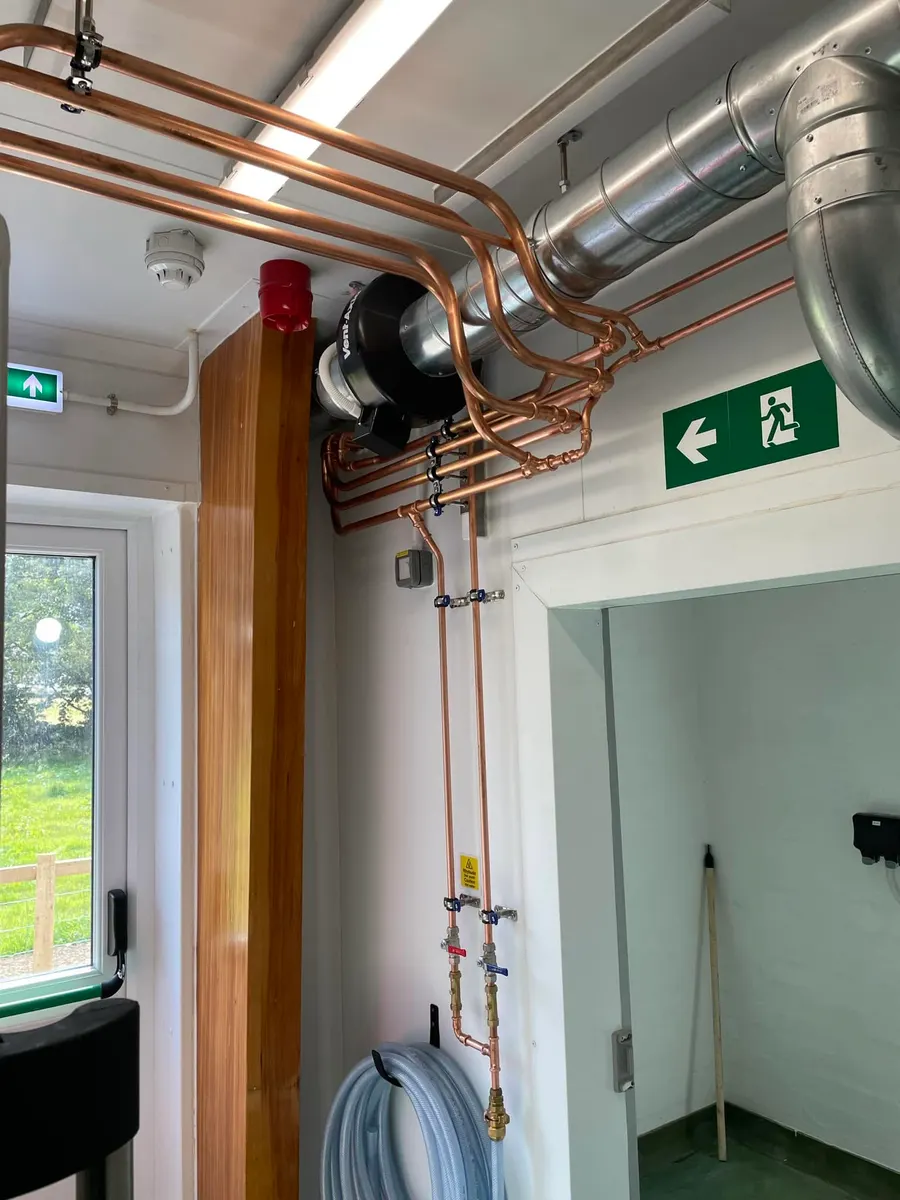 Copper pipework and ventilation ducting in a commercial building corridor